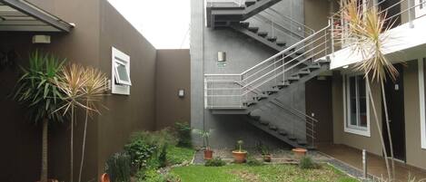 A courtyard with a staircase, potted plants, and a small garden area.