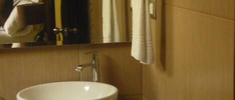 Une salle de bain avec un lavabo blanc, un miroir et deux serviettes suspendues Ă un porte-serviettes.