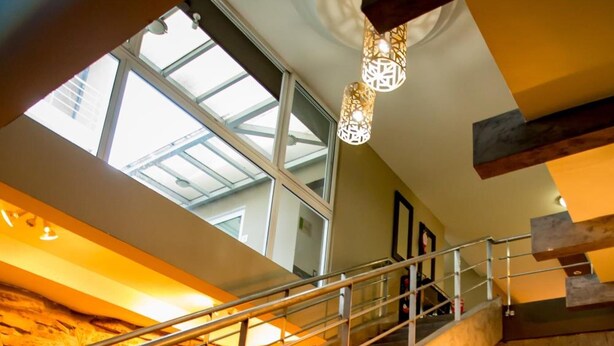 A staircase with a metal railing leading to a higher level, a skylight above, and large spherical objects on the lower level. - Terra Bella Hotel Boutique (San Salvador)