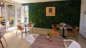 A modern indoor dining area with tables and chairs, a green leafy wall, and a sign for Terra Bella Hotel Boutique. - Terra Bella Hotel Boutique (San Salvador)