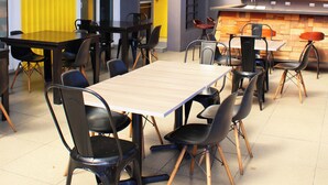 A restaurant with a high ceiling, exposed beams, and a mix of wooden and metal furniture. - Terra Bella Hotel Boutique (San Salvador)
