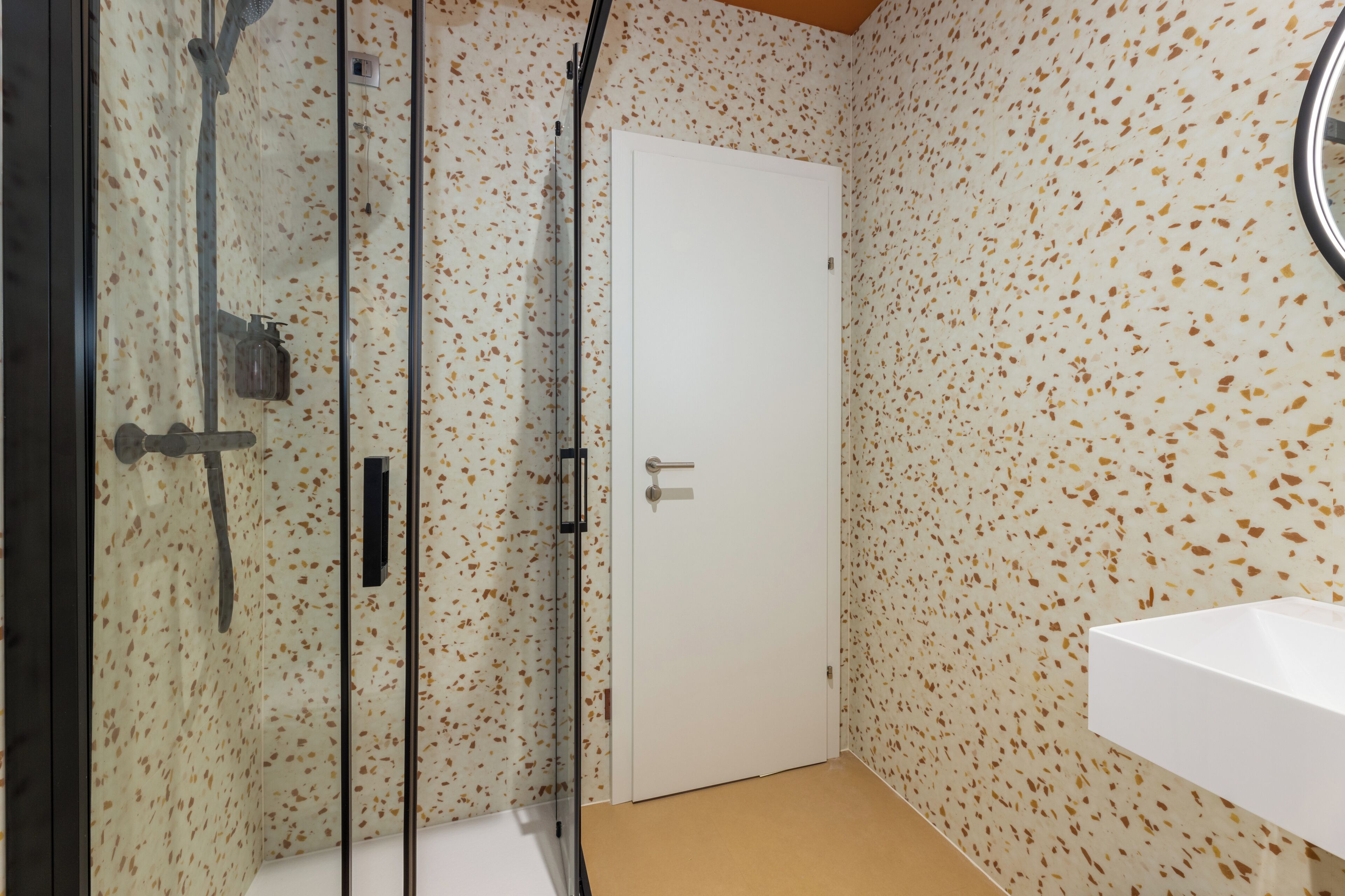 Un baño con ducha, una puerta blanca y un lavabo.