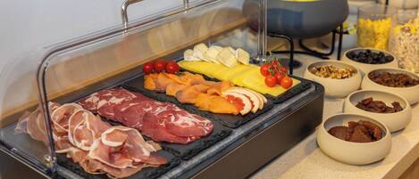 A buffet with various meats, cheeses, fruits, and nuts.