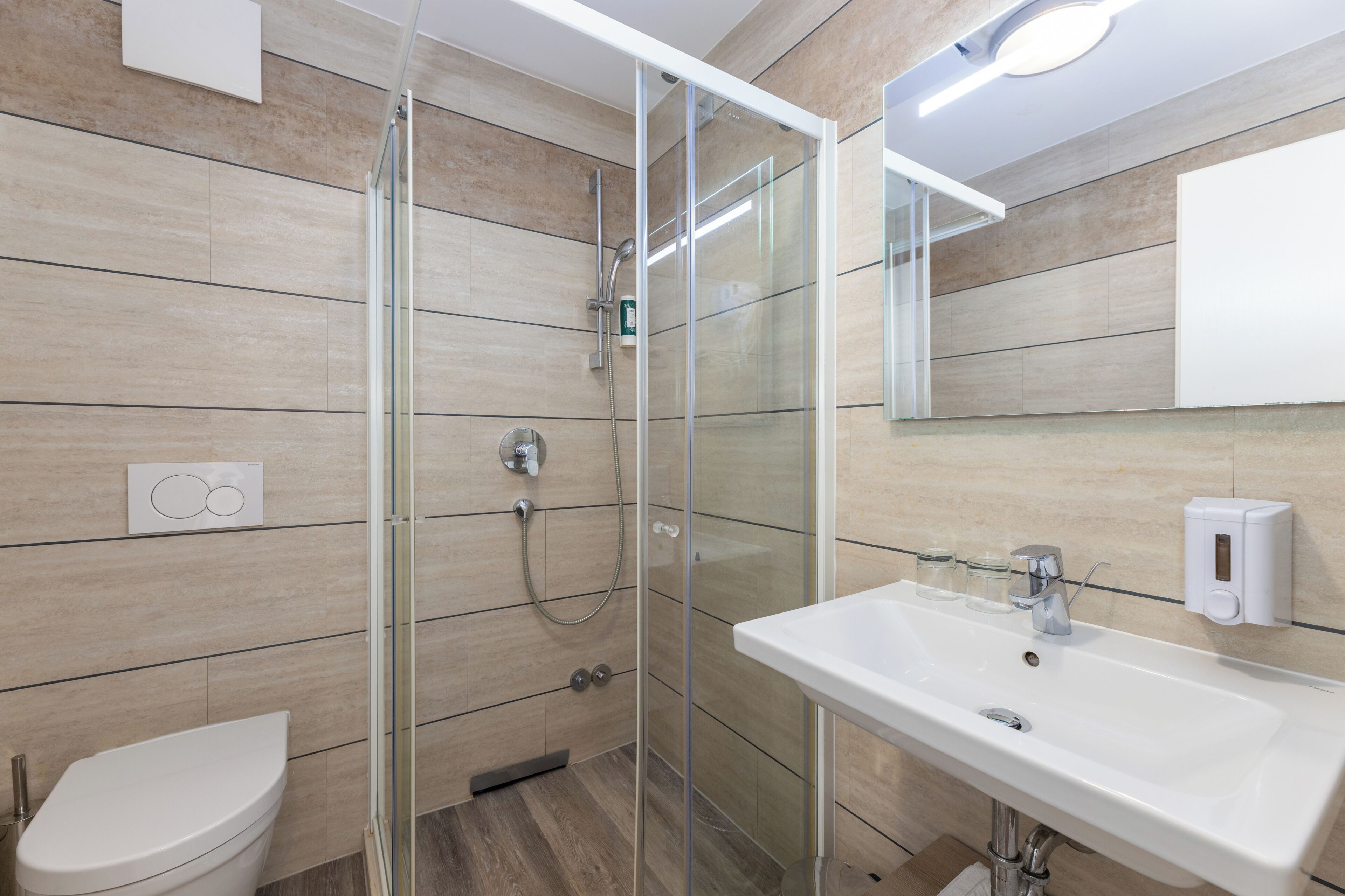 A modern bathroom with a glass-enclosed shower, a white sink, and a toilet.
