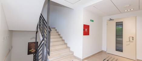 A modern interior with a staircase, a red emergency exit sign, and a door with a 'FULL HERE' sign.