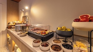 Un buffet proposant une variété de plats, notamment des fruits, des viandes et des plats préparés.