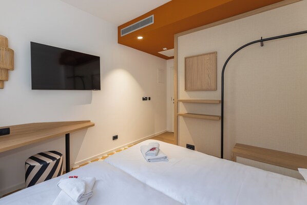A hotel room with a bed, a flat-screen TV, a wooden desk, a chair, and a wardrobe. - B&B Sol (Dubrovnik)
