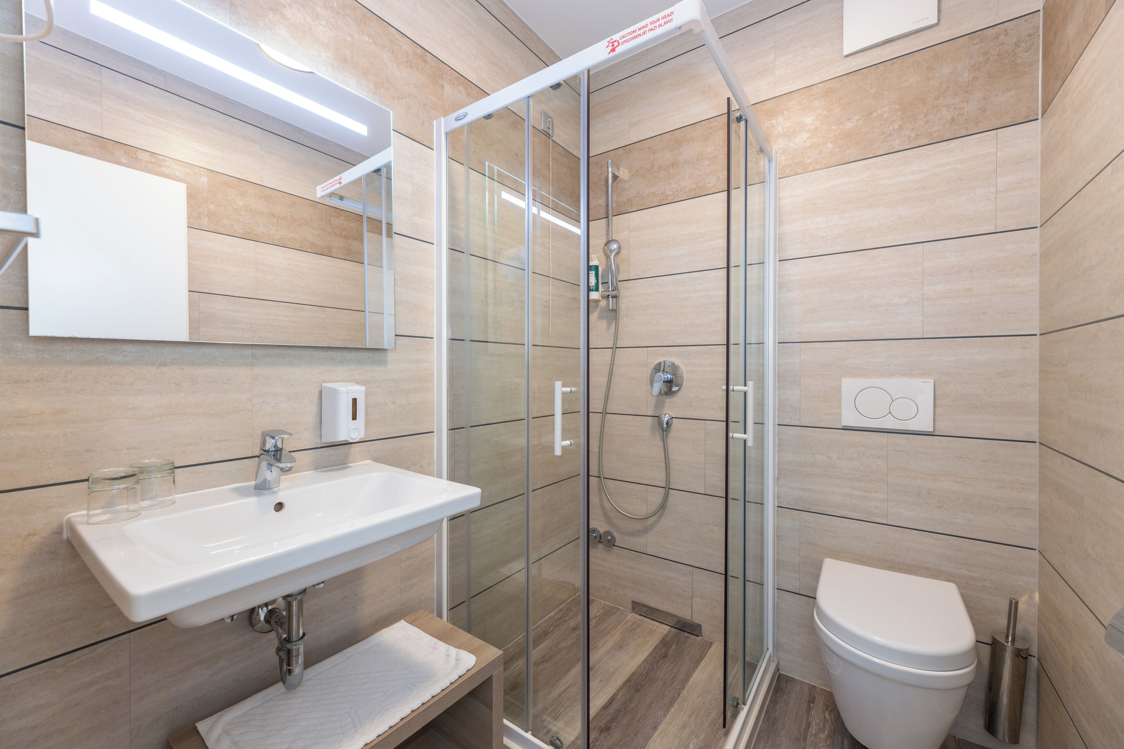 A modern bathroom with a glass-enclosed shower, a white sink, and a toilet.
