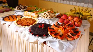 A buffet table with various food items including pies, fruits, and pastries. - Marlim Porto Hotel (Porto Seguro)
