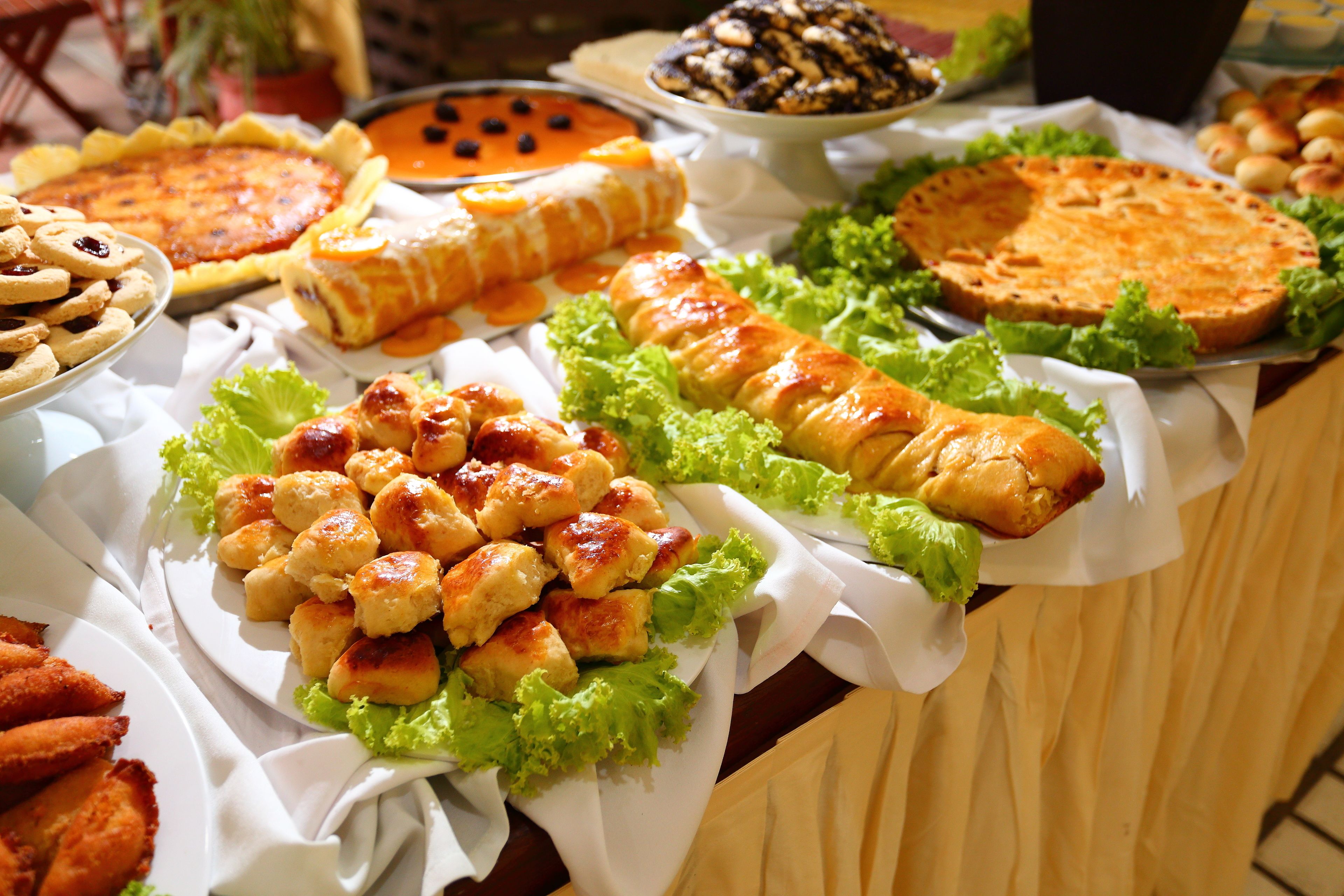 Une table de buffet proposant divers plats, notamment une quiche, une tarte et une pâtisserie.