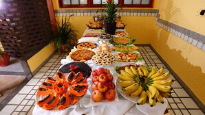 A buffet table with various fruits and pastries. - Marlim Porto Hotel (Porto Seguro)