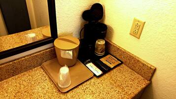 A countertop with a coffee maker, a scale, and a cup of coffee.