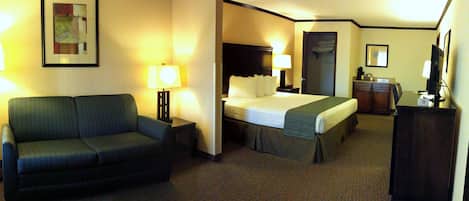 Una habitación de hotel con cama, sofá, escritorio y televisión.