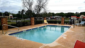 Una piscina con un cartel que indica 'no diving' de 3 pies, sillas de descanso y un muro de ladrillo.