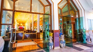 Een hotel lobby met grote glazen deuren, een receptiebalie en decoratieve vazen.