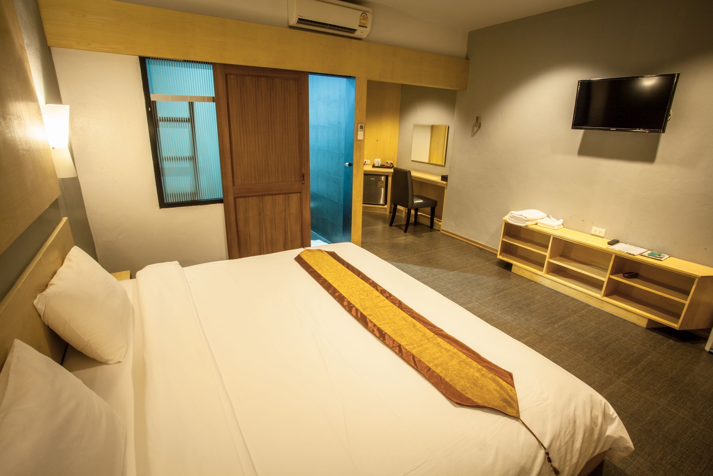 Une chambre d’hôtel équipée d’un lit, d’un bureau, d’une chaise, d’une télévision et d’une armoire.