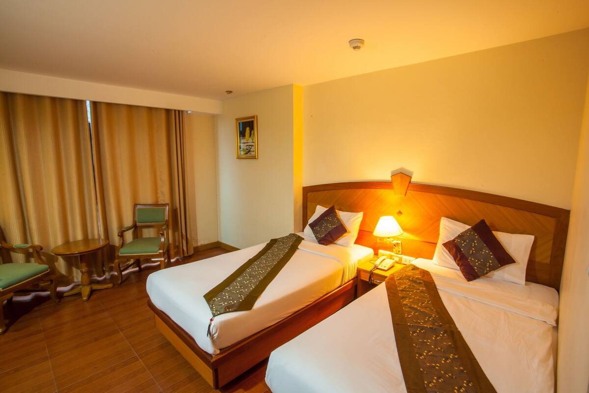 Een hotelkamer met twee bedden, een bureau, een stoel en een lamp.