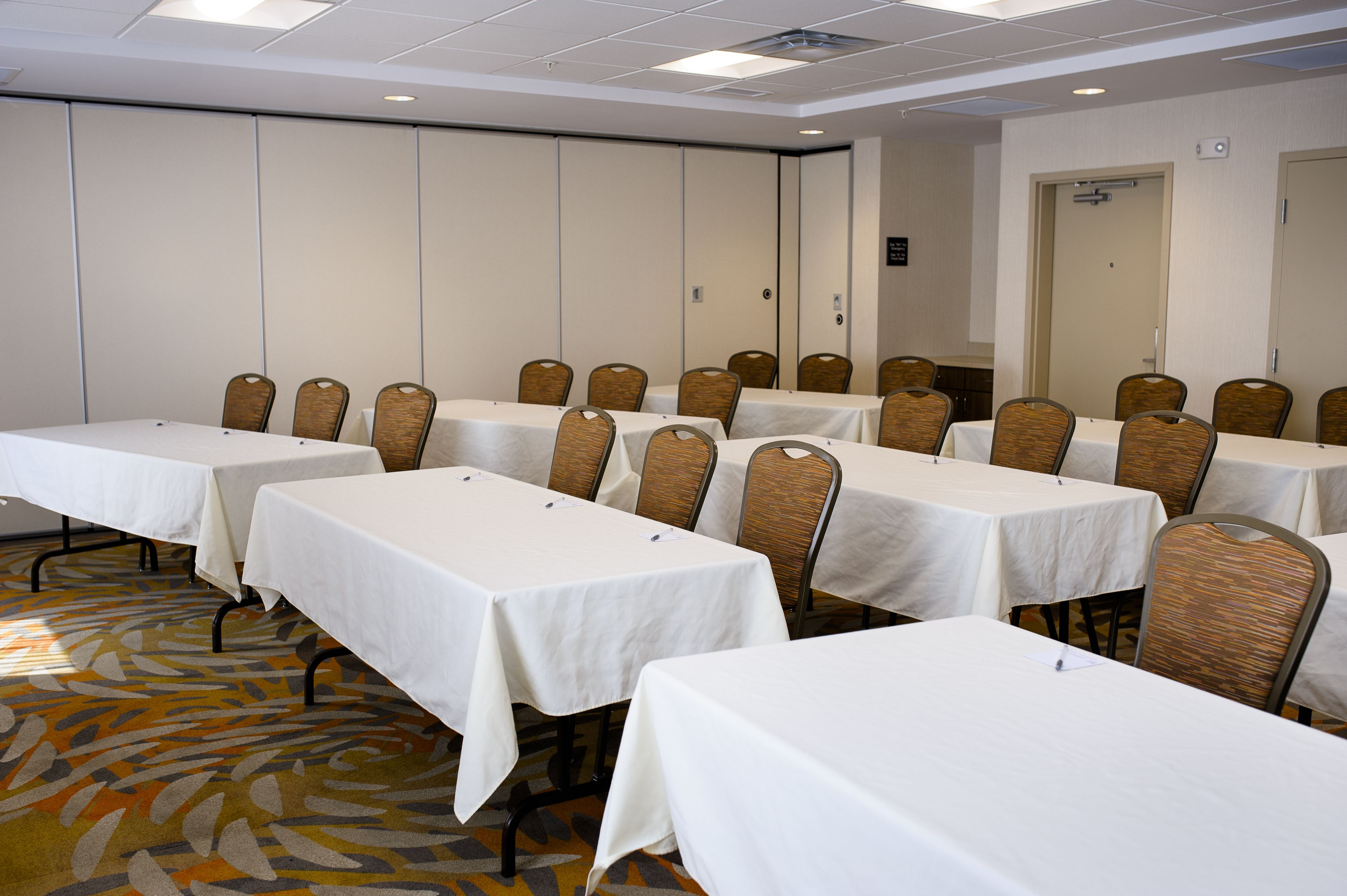 Une salle de conférence dotée de plusieurs tables et de nombreuses chaises, disposées en rangées.