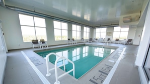 A large indoor swimming pool with clear markings, sunlit windows, and lounge chairs. - Hampton Inn & Suites by Hilton Truro (Millbrook First Nation Reserve)
