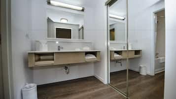 Een moderne badkamer met een grote spiegel, een houten wastafelmeubel en een aparte douchehoek.