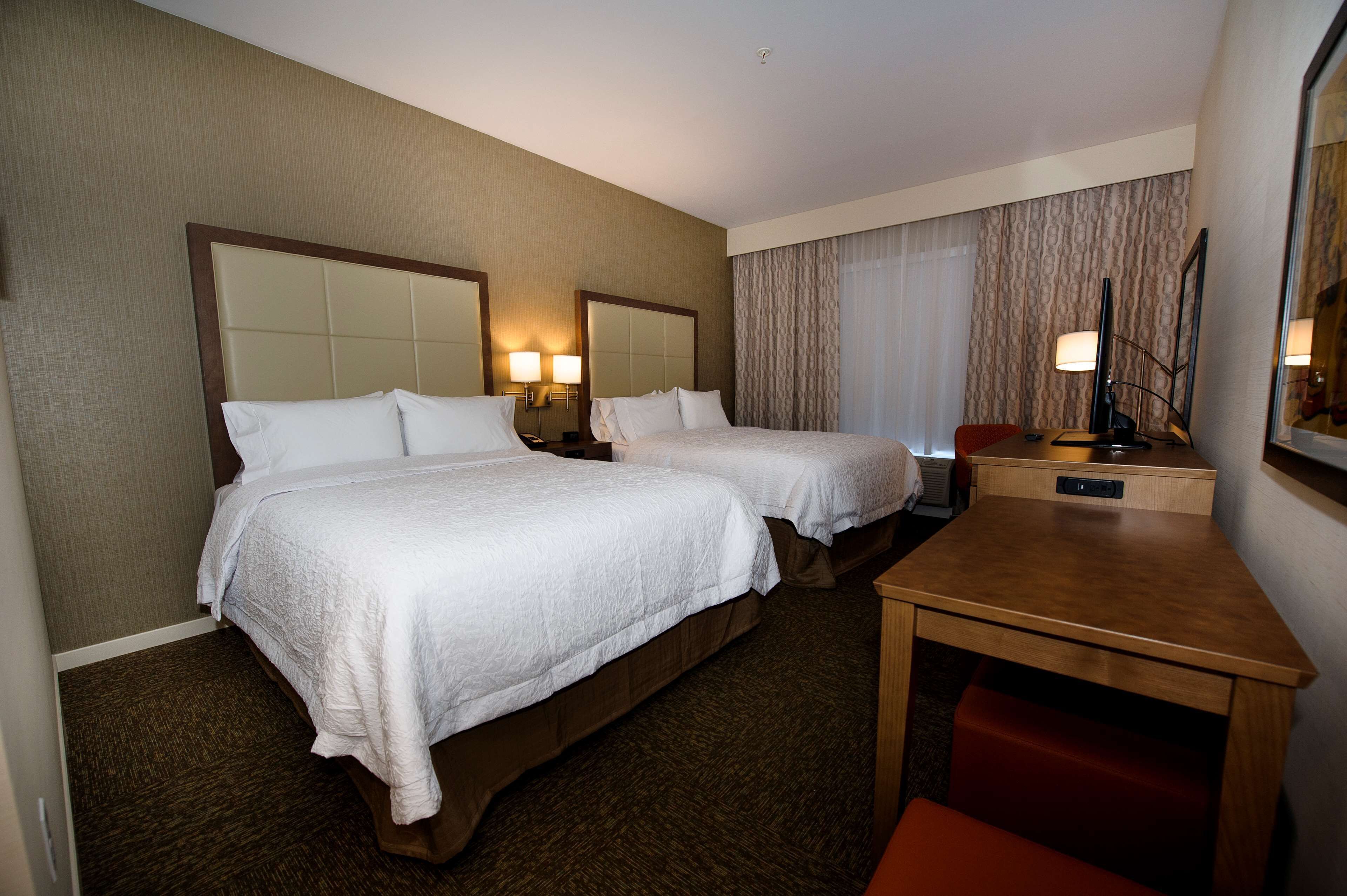 A hotel room with two beds, a desk, and a chair.