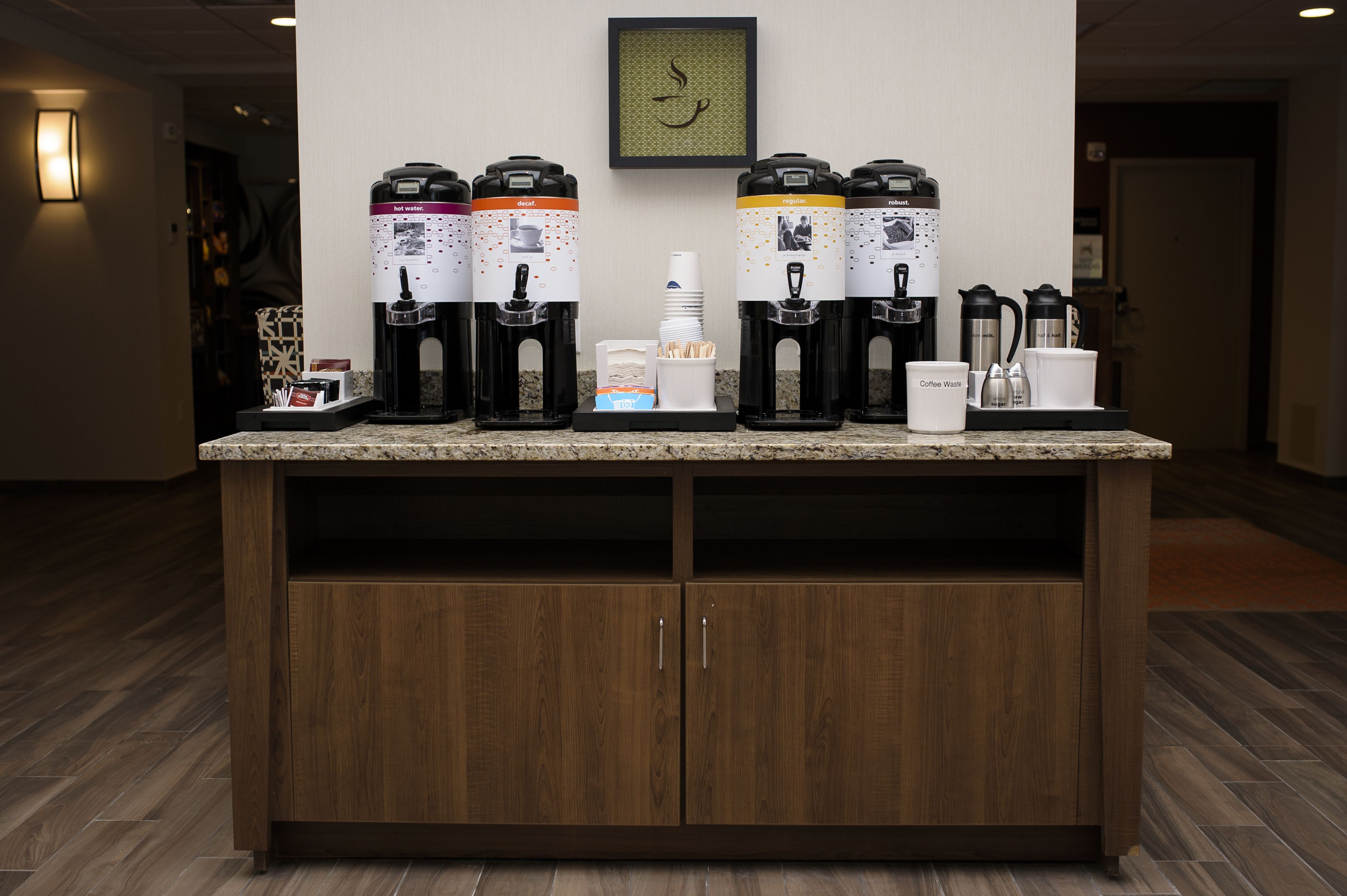 A coffee station with multiple dispensers, a coffee pot, and a coffee maker on a granite countertop.