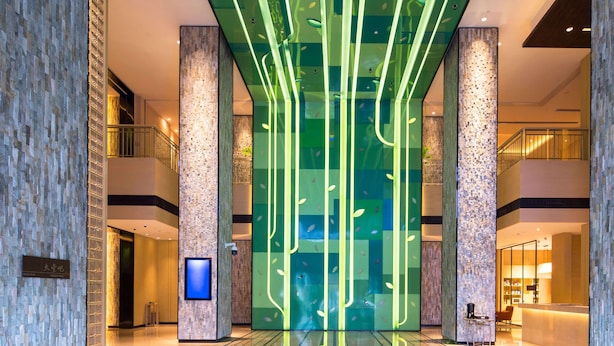 Eine moderne Lobby mit Glastrennwand, einer Rezeption und einer Treppe.