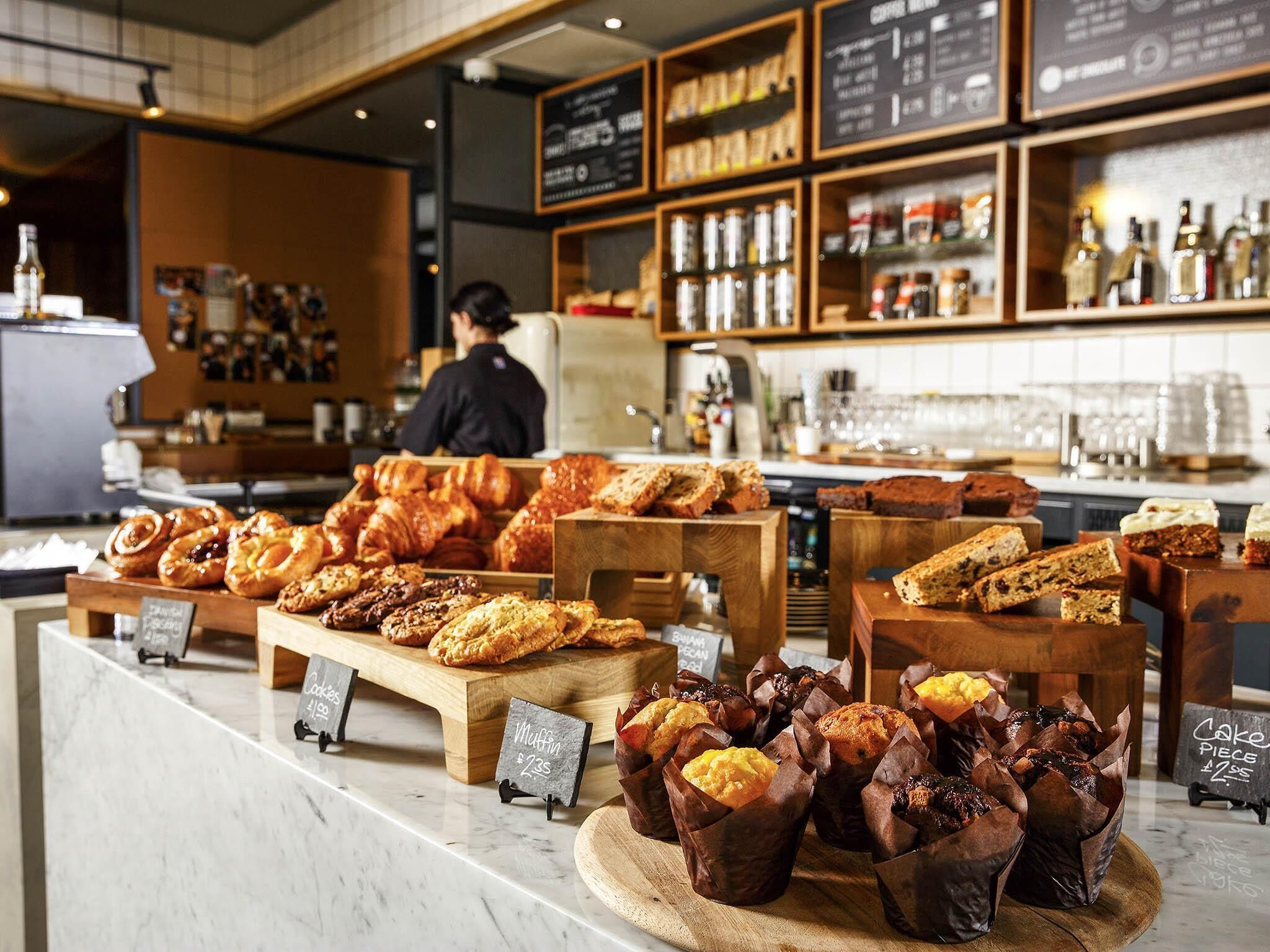 Una vetrina di panetteria con diversi prodotti da forno e un caffè sullo sfondo.