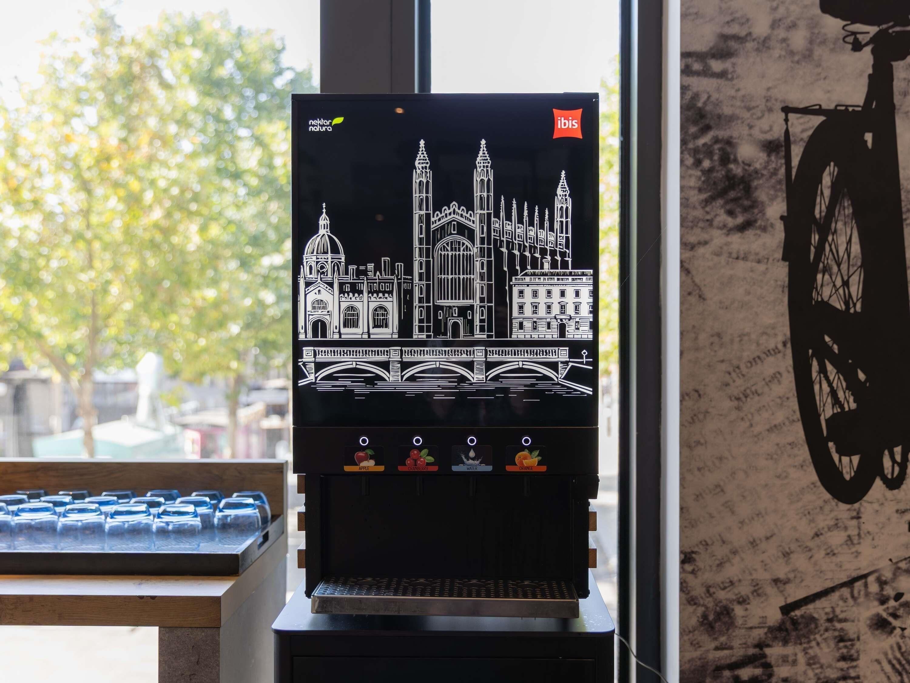 Una cafetera con diseño de paisaje urbano, vista a la ventana y silueta de una bicicleta en la pared.