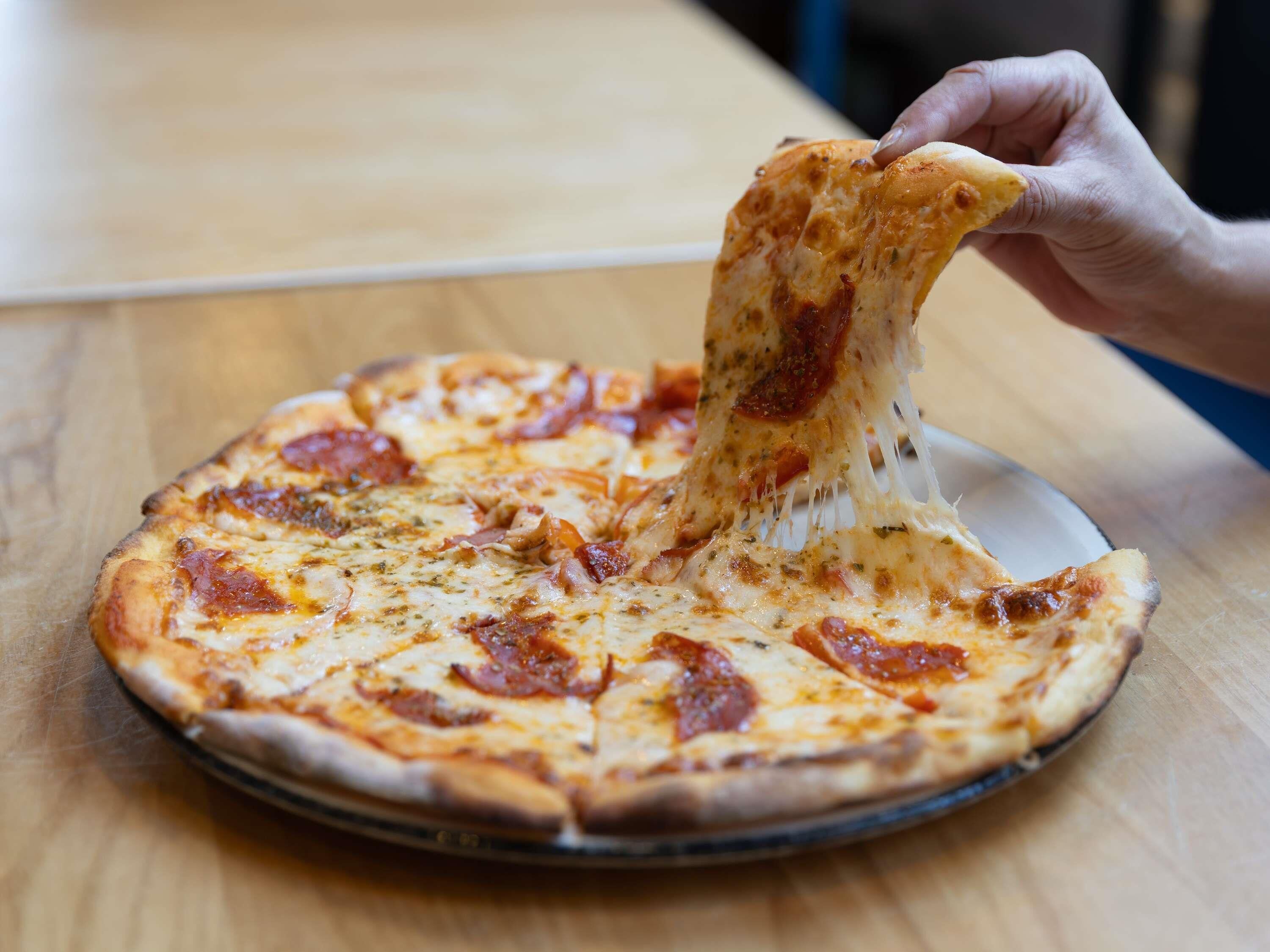 A pizza with pepperoni on a wooden table.