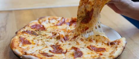 A pizza with pepperoni on a wooden table.