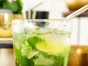 A glass of a green-colored beverage with mint leaves and ice cubes. - ibis Cambridge Central Station (Cambridge)