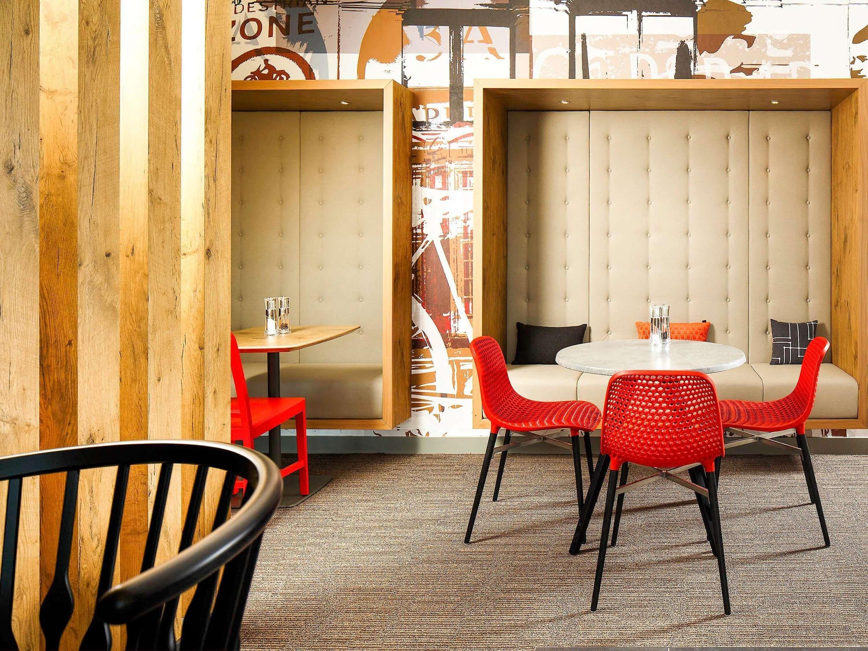 Interior de restaurante con zona de mesas tipo camarote, una mesa redonda con sillas y una silla roja al frente.