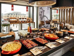 Un bufé con diferentes opciones de comida y vistas a la ciudad a través de amplios ventanales.