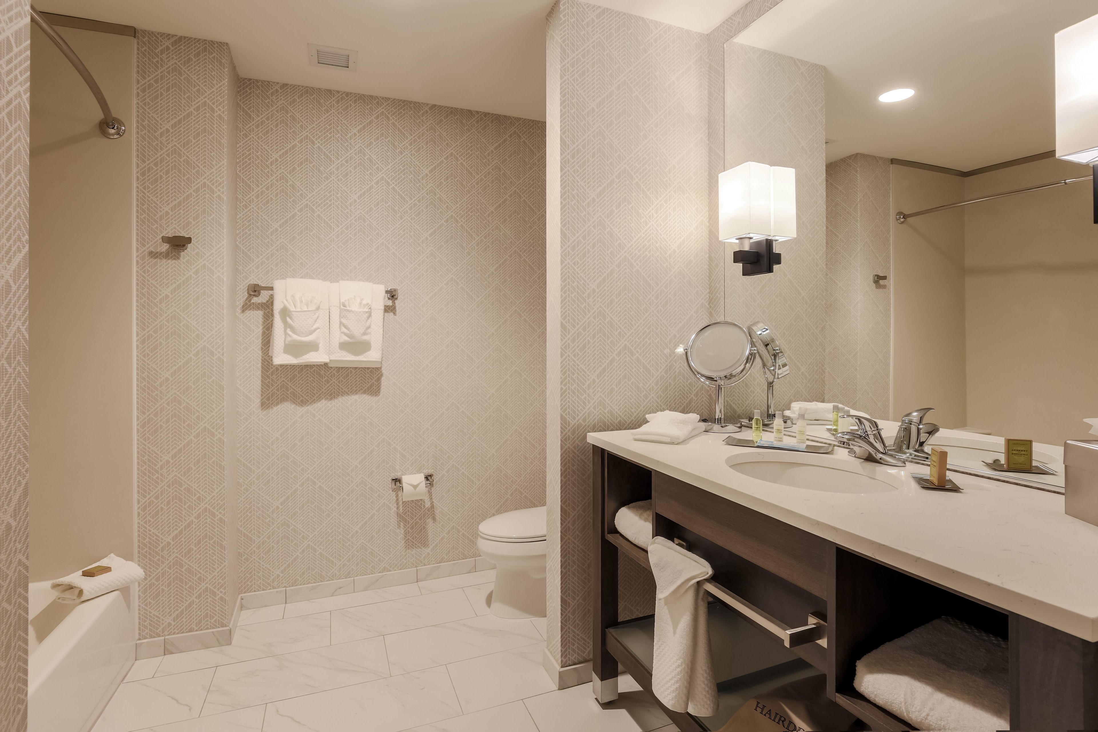 Ein modernes Badezimmer mit Dusche, Toilette und Waschtisch mit Spiegel und Waschbecken.