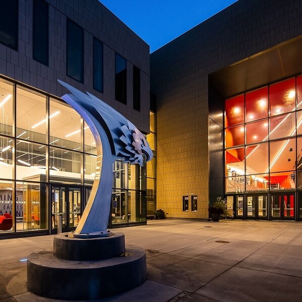 A modern building with a prominent sculpture in front, large glass windows, and a brightly lit entrance. - DoubleTree by Hilton Evansville (Evansville)