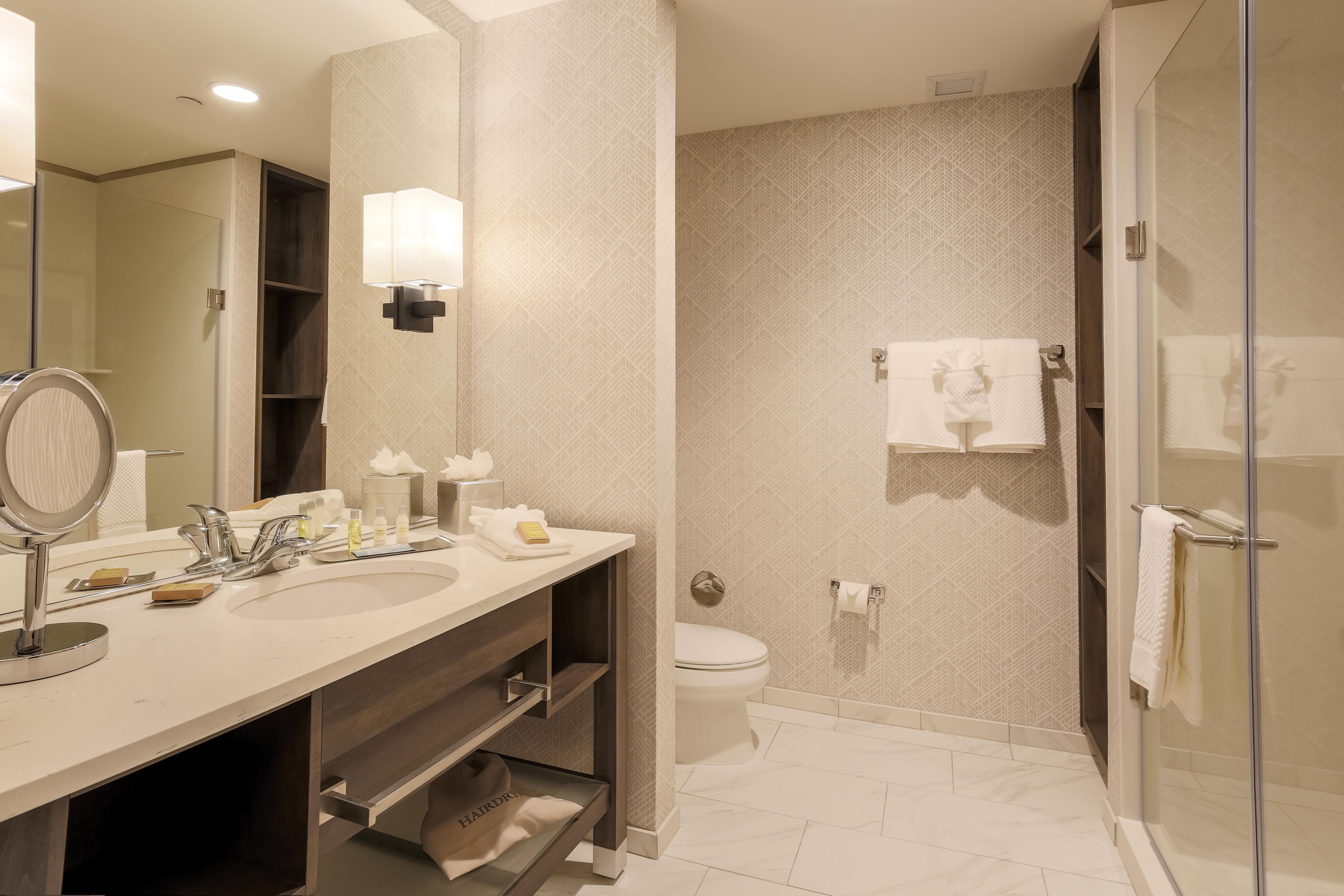 A modern bathroom with a vanity, sink, mirror, and a glass-enclosed shower area.