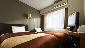 Une chambre d’hôtel avec deux lits, un bureau avec un ordinateur et un appareil de climatisation.