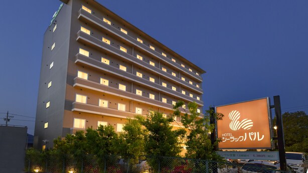 Un hôtel à plusieurs étages, doté de fenêtres illuminées et d’un grand panneau publicitaire affichant le nom de l’hôtel.