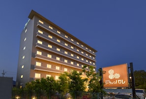 Un hotel de varios pisos con ventanas iluminadas y un gran anuncio luminoso que muestra el nombre del hotel.
