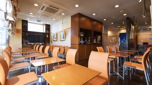 Un espace repas moderne doté de plusieurs tables et chaises, d’un téléviseur à écran plat et d’armoires en bois.