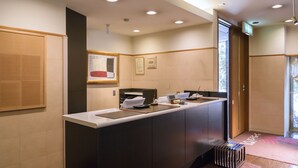Un comptoir d’accueil, un petit espace d’attente et une porte donnant sur une autre pièce.