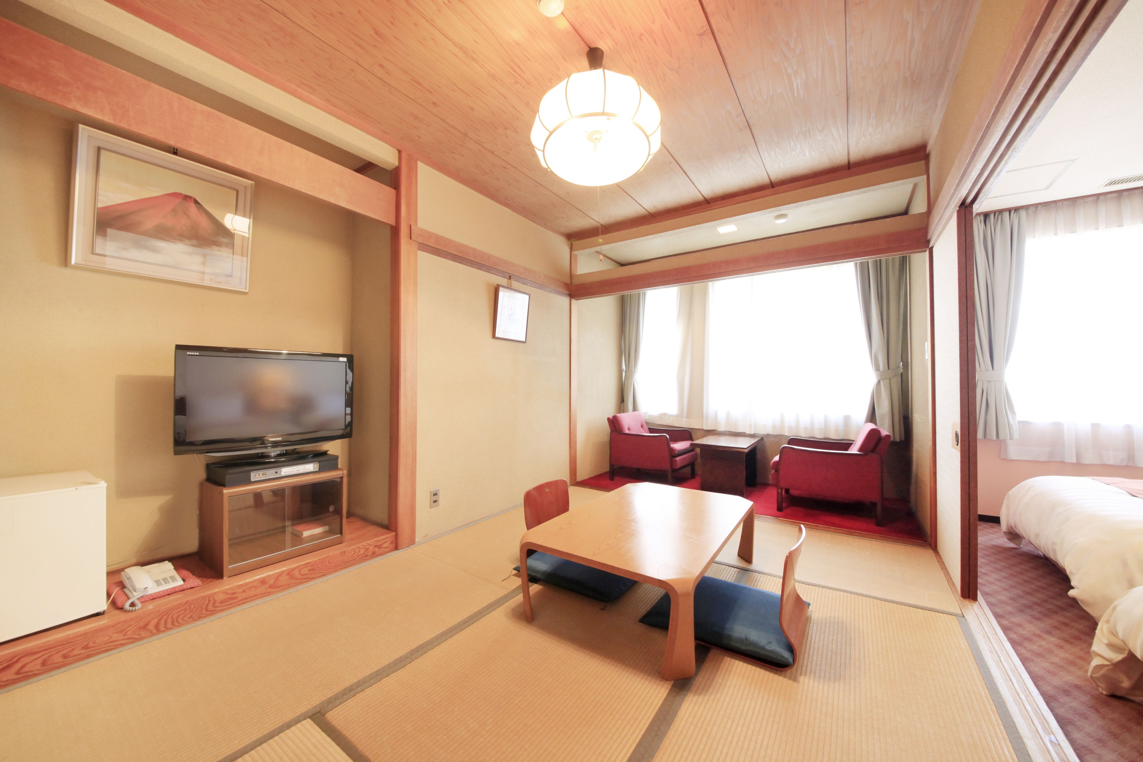 Una habitación de hotel con televisión, mesa de comedor, sofá y cama.