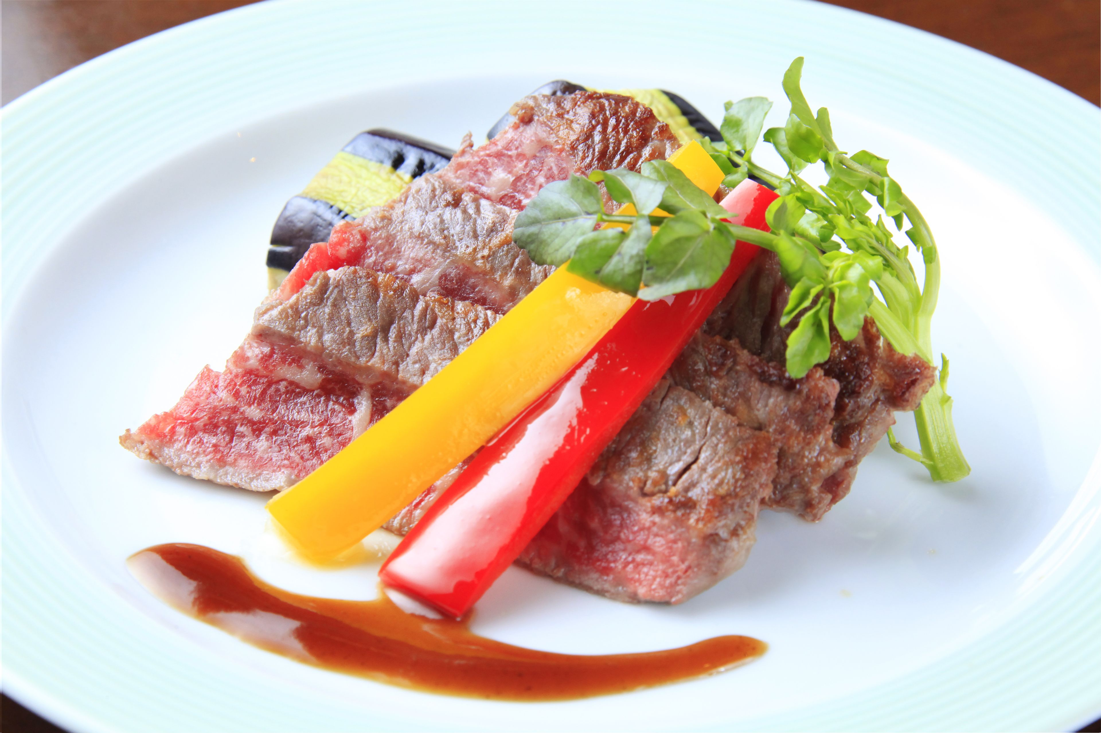 A plate of food with steak, vegetables, and sauce.