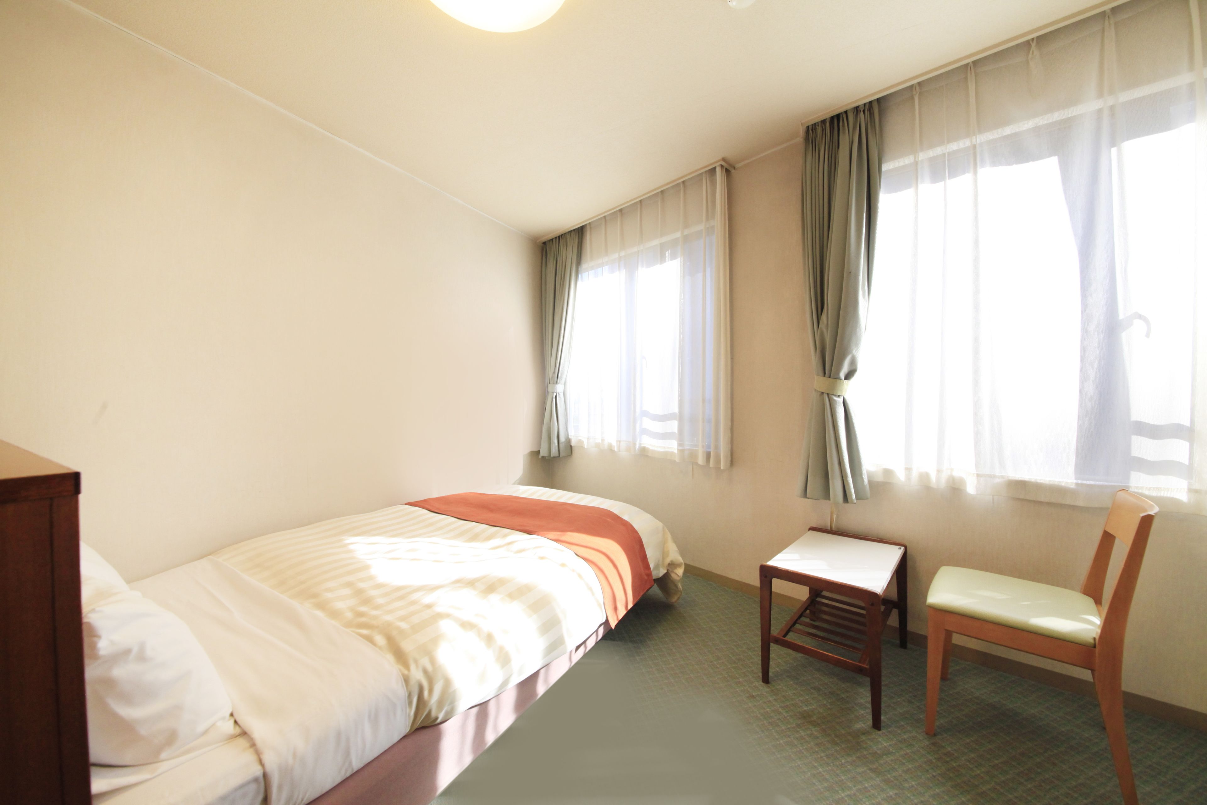 Une chambre d’hôtel avec un lit, une petite table et une chaise.