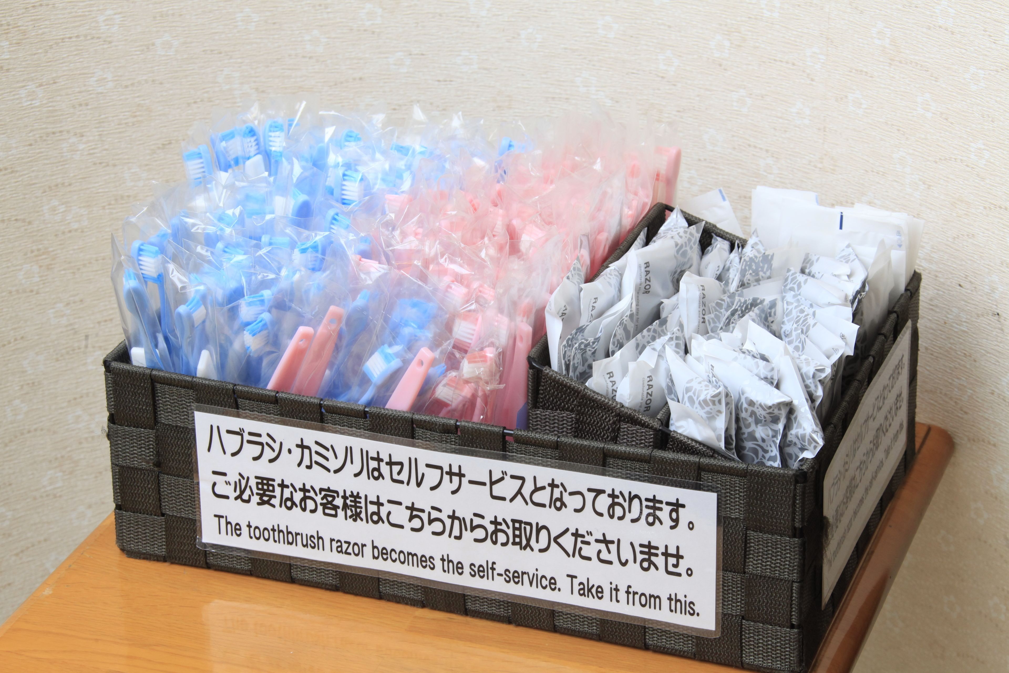 A box of toothbrushes and razors with a sign indicating they are for self-service.