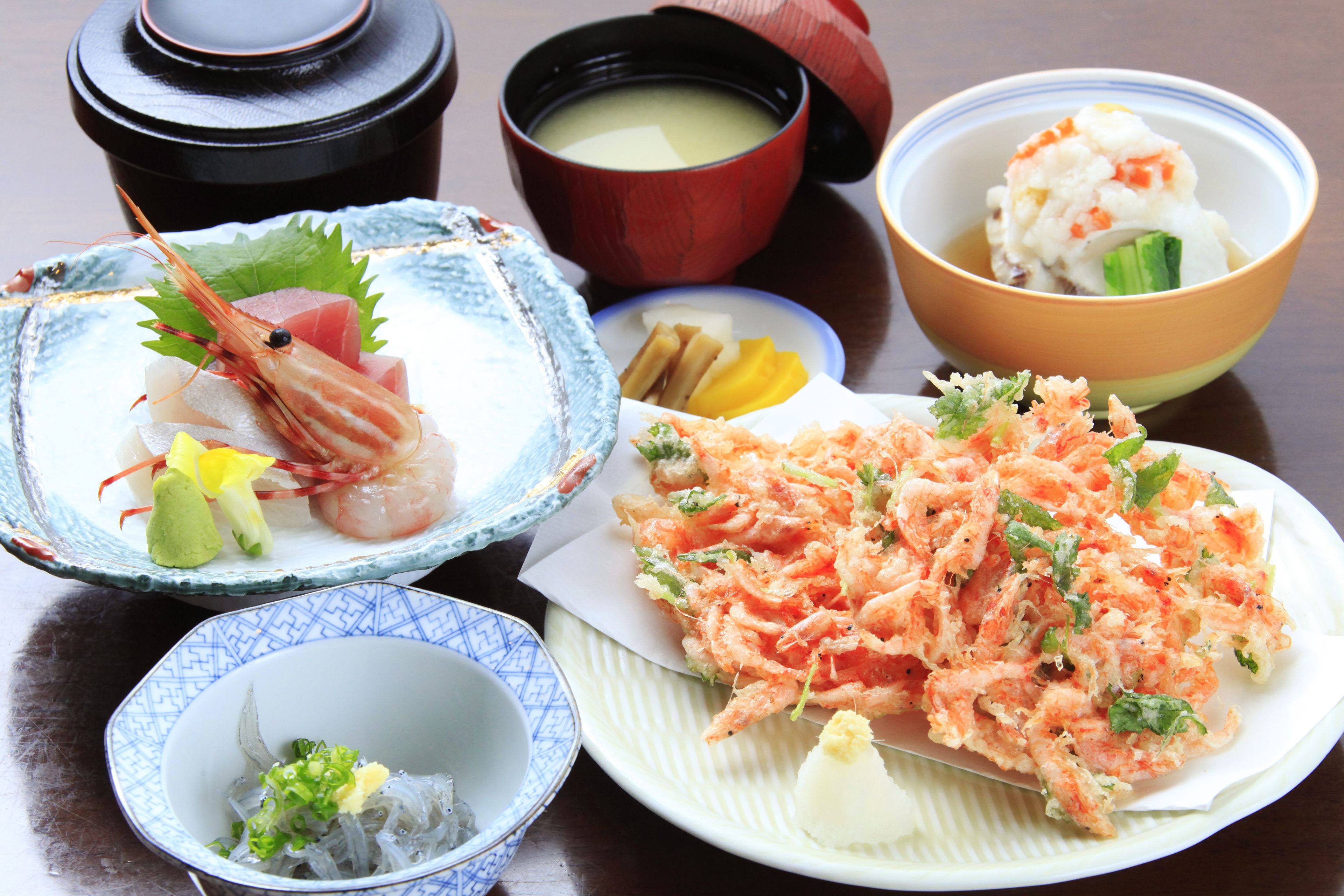 A variety of Japanese dishes including sashimi, tempura, and a bowl of soup.