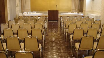 Konferenssisali, jossa on riveissä tuoleja pitkän pöydän ympärillä ja puhujapönttö salin etuosassa.
