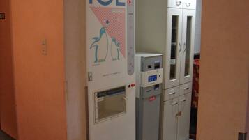 A hallway with an ice machine and a vending machine, cabinets, and a door with a number sign.