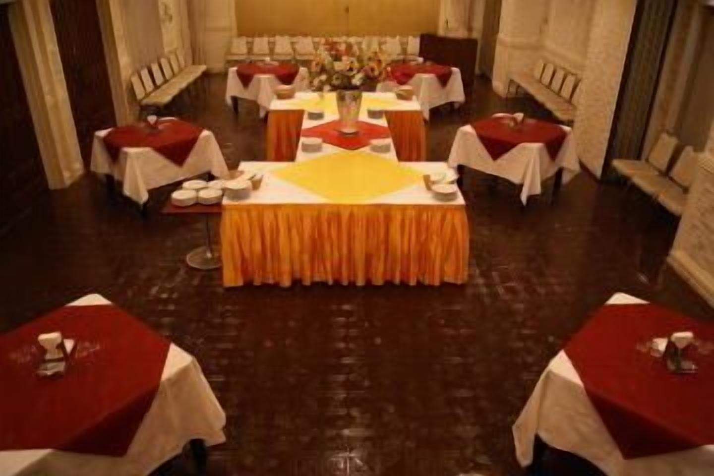 Une salle de banquet avec des tables rondes, chacune recouverte d’une nappe rouge et agrémentée d’un chemin de table blanc.
